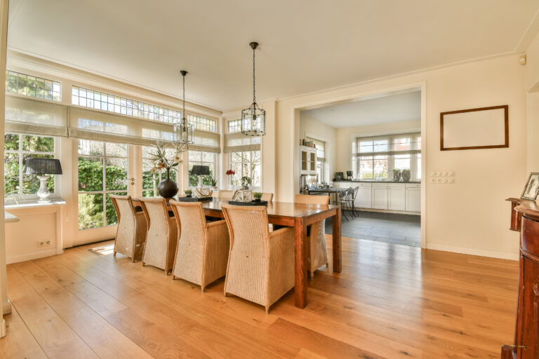 a dining room with wood flooring and large windows that look out onto the garden outside, as well in this photo