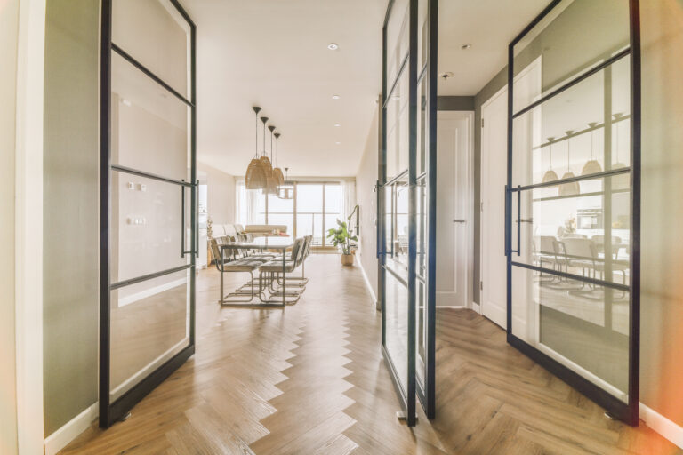 Corridor of contemporary apartment with opened doorway leading to living room